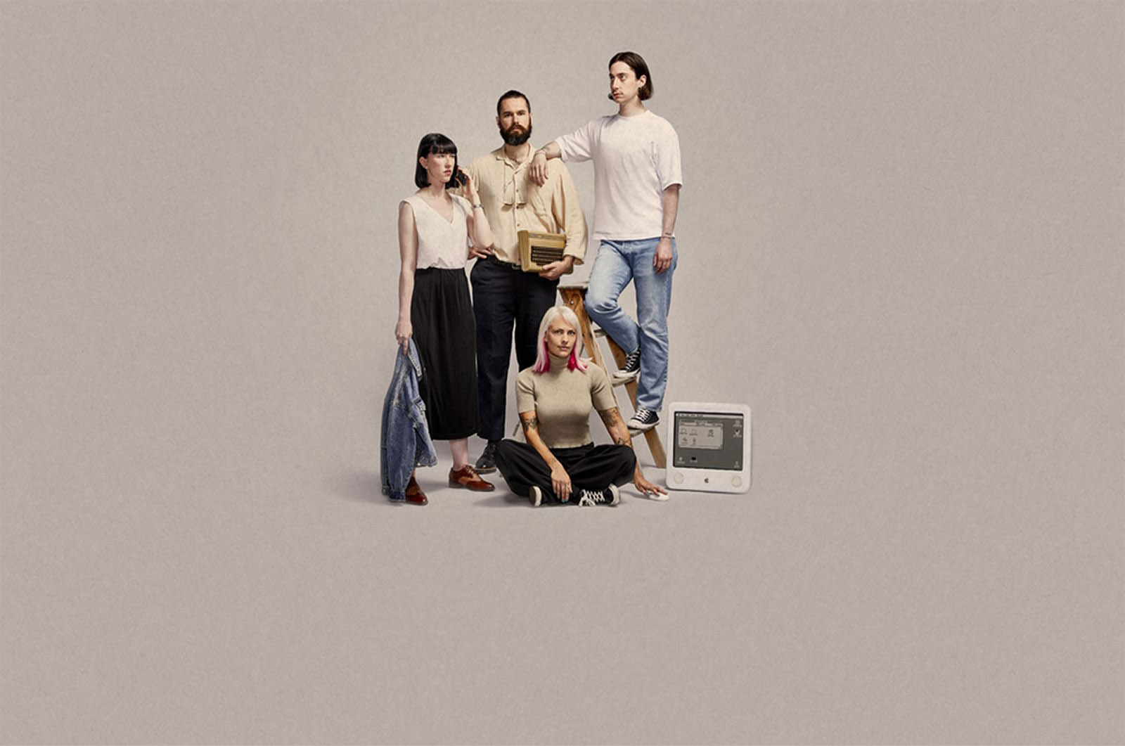 Group of people in older style fashion around an Apple computer