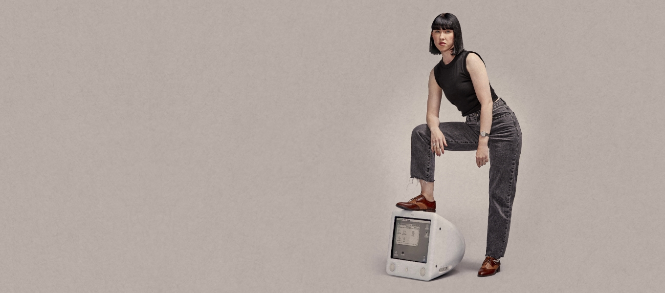 Lady in jeans standing with one foot on old mac computer